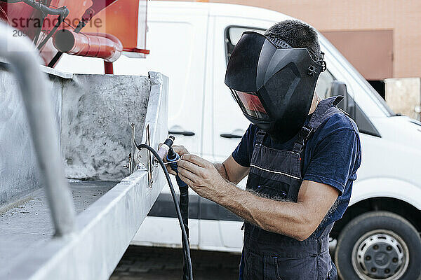 Man repairing vehicle outside garage