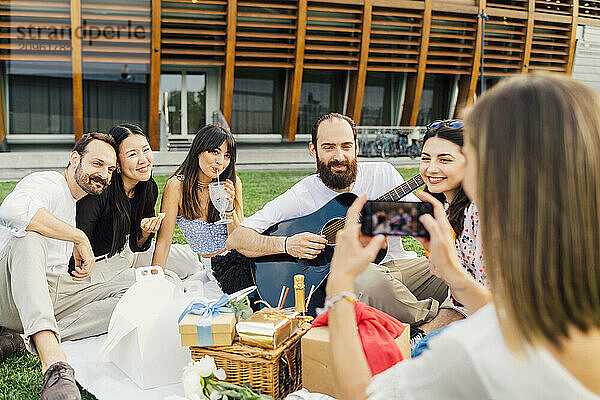 Woman photographing friends with smart phone in park