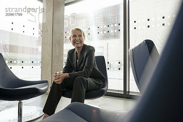 Happy senior businessman sitting on chair at office