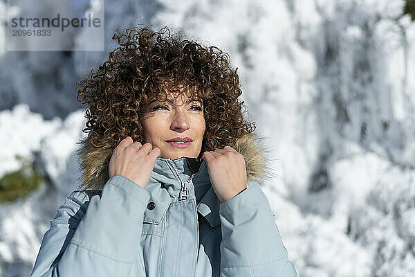 Woman with curly hair holding parka jacket in winter