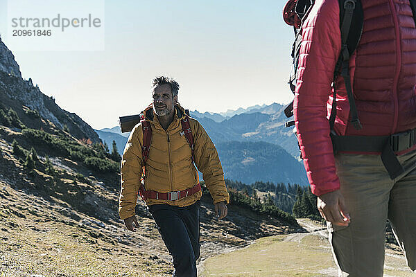 Man in warm clothing hiking with friend on mountain