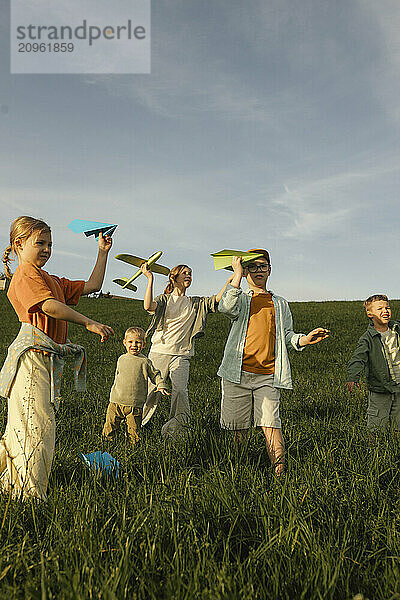 Siblings playing with paper plane in meadow