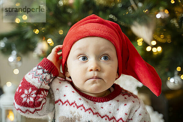 Cute baby boy wearing Santa hat on Christmas day at home