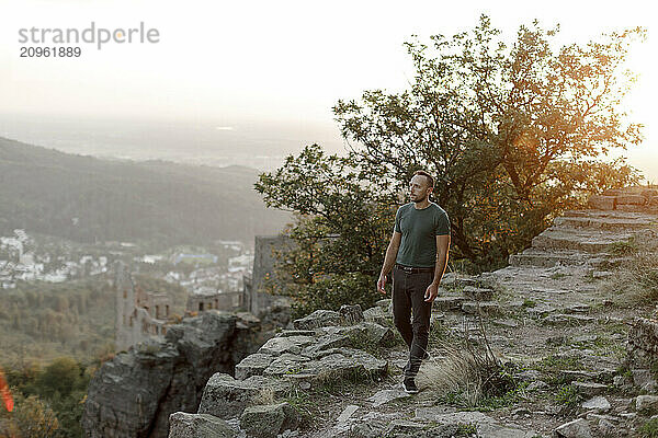 Man walking on rocky footpath at sunset