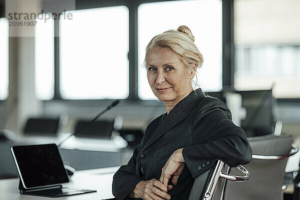 Smiling senior businesswoman sitting on chair at office