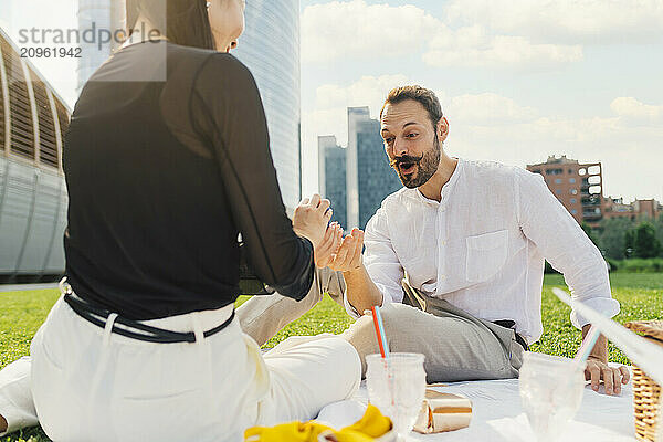 Woman surprising man with gift under sky