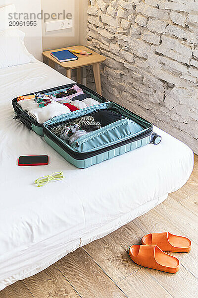 Open suitcase on bed in hotel room