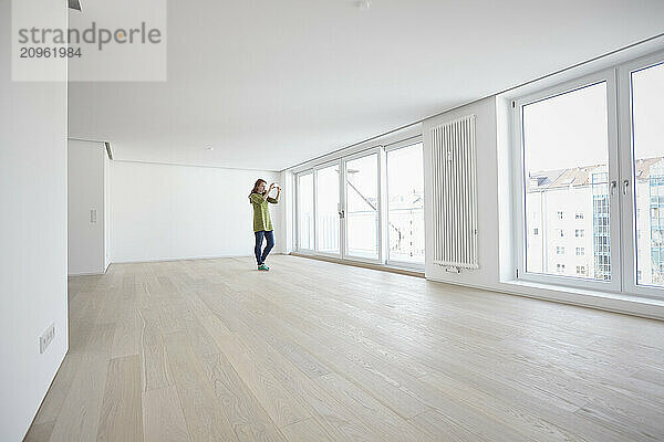 Young woman standing and taking picture of new apartment