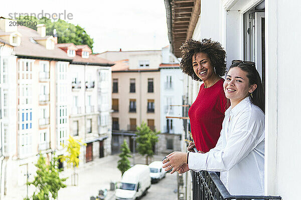 Cheerful friends standing in balcony at hotel