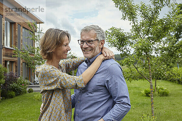 Happy woman with arm around man in back yard