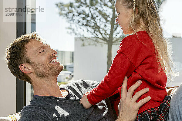 Smiling father playing with daughter at home