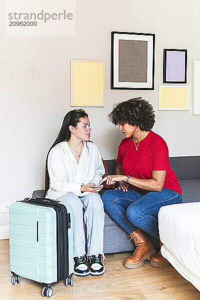 Multiracial friends sitting on sofa and discussing in hotel room