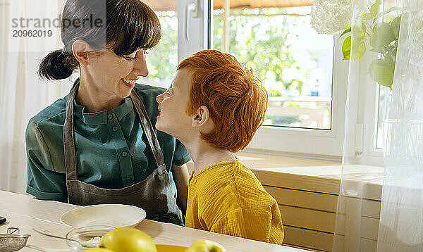 Playful mother and son in kitchen near window