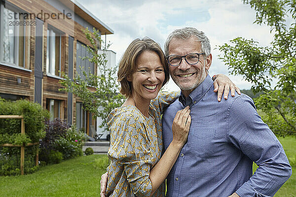 Smiling woman with arm around man in back yard