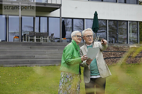 Senior couple standing in garden makong plans