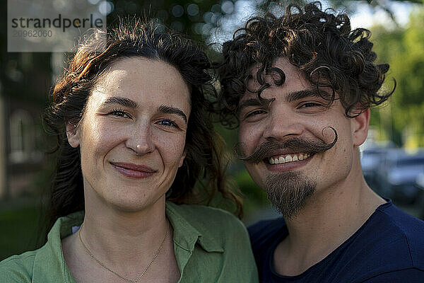 Smiling man with curly hair next to girlfriend