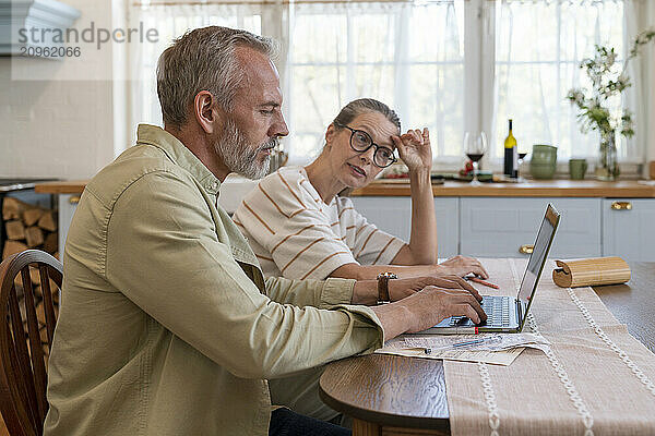 Woman discussing with man preparing bills over laptop at home