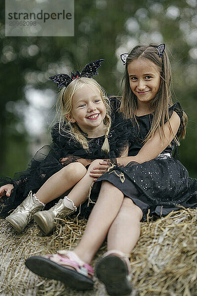 Happy sibling sitting together on haystack