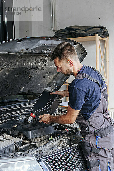 Mechanic changing motor oil in garage