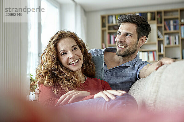 Cheerful couple sitting on sofa at home