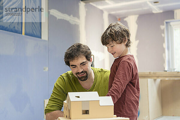 Father and son standing near model house in new apartment