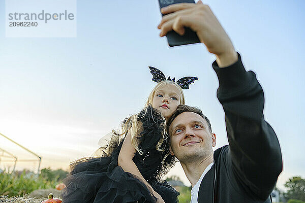 Happy father taking selfie with daughter at agricultural field