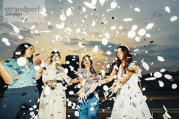 Cheerful friends celebrating together and having fun with confetti