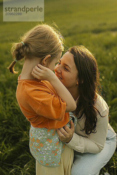 Mother embracing daughter in meadow