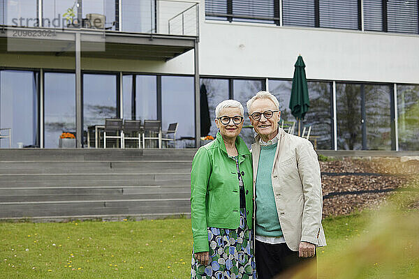 Portrait of senior couple in front of their home