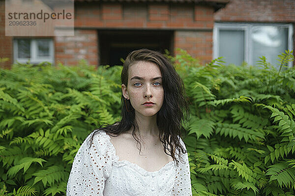 Teenage girl standing in garden outside house