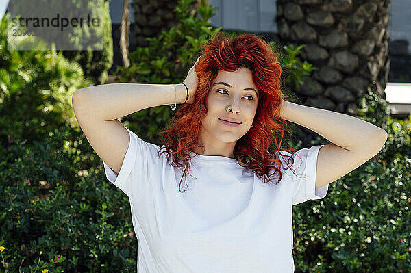 Smiling redhead woman with head in hands