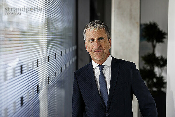 Businessman in suit standing near glass wall at office