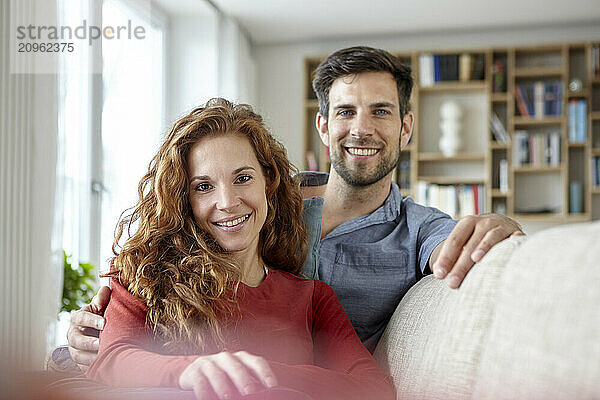 Happy smiling couple sitting on sofa at home