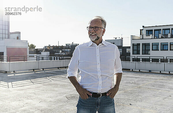 Smiling man with hands in pockets standing on terrace