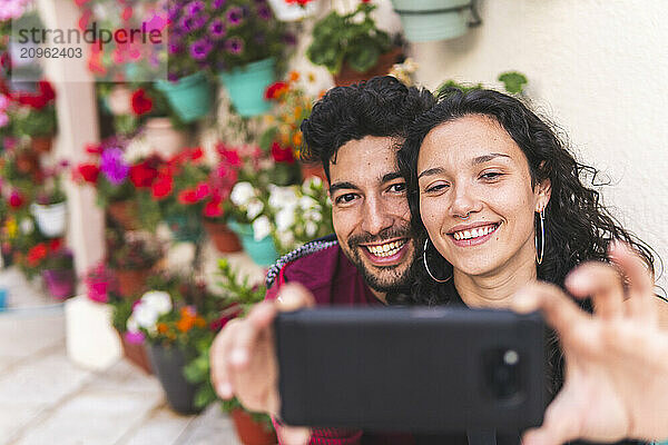 Smiling woman taking selfie through smart phone with boyfriend