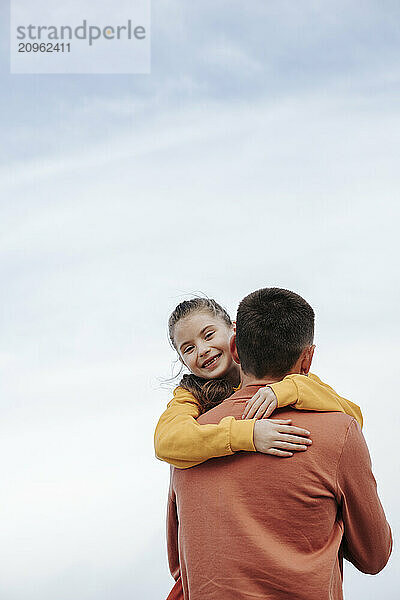 Cheerful girl embracing father at beach