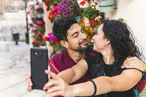 Young woman taking selfie with boyfriend through smart phone at street