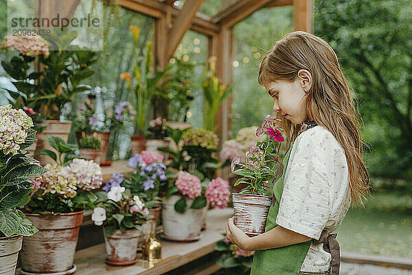 Long hair girl smelling flower in plant nursery