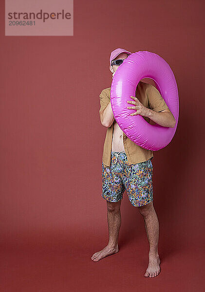 Young man posing with swimming float against brown background