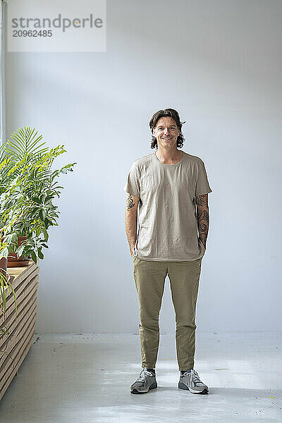 Smiling man standing with hands in pockets at home