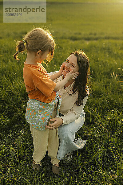 Happy girl playing with mother at meadow