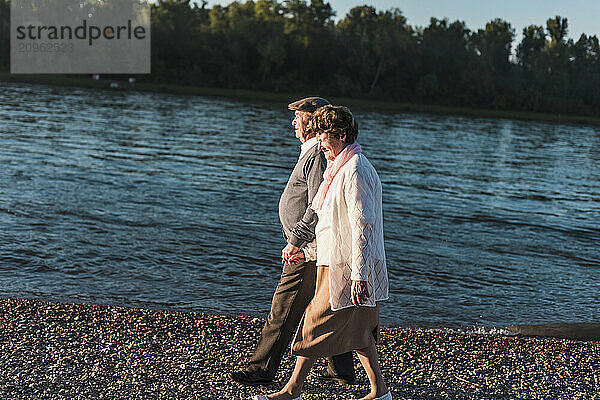 Senior couple holding hands and walking near river