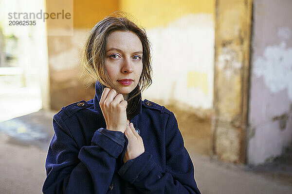 Blond woman wrapped in jacket standing on road in alley