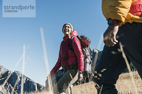 Happy woman walking through meadow with friend on mountain