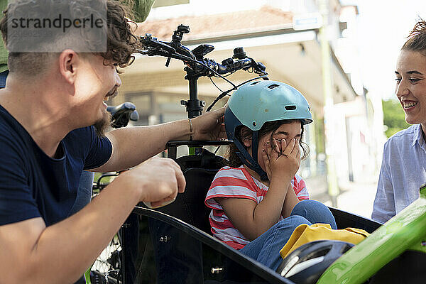 Family enjoying with girl sitting in cargo bike