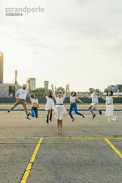 Cheerful friends jumping together and having fun on road