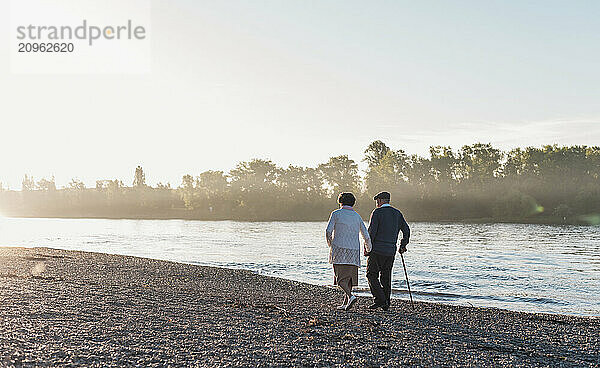 Senior couple walking near river at sunset