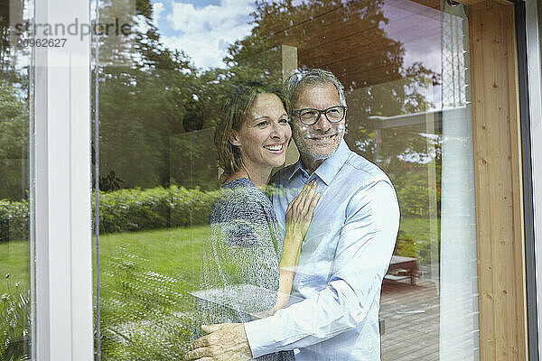 Smiling couple standing and looking out of window