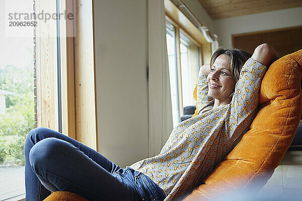 Smiling woman sitting on lounge chair at home