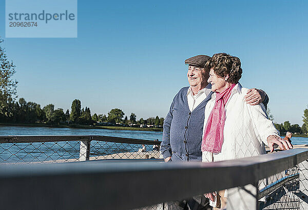 Happy senior couple standing together near river in park